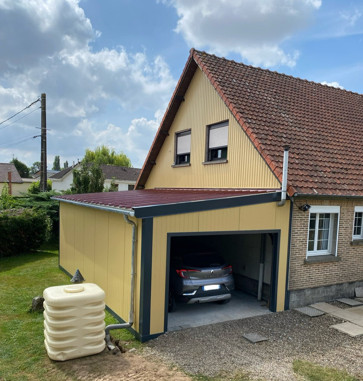 Une maison avec un garage en panneaux sandwich de bardage